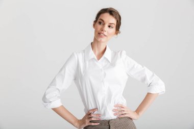 Elleri belinde poz veren, beyaz arka planda yalnız, baştan çıkarıcı bir kadının görüntüsü.