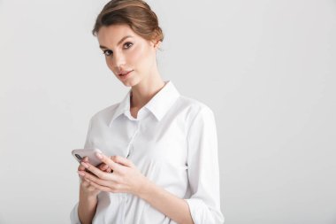 Beyaz arka planda izole edilmiş, cep telefonunda yazan ciddi ve güzel bir kadın görüntüsü