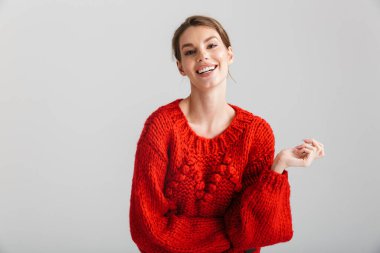 Kırmızı kazaklı neşeli bir kadın görüntüsü beyaz arka planda izole edilmiş kameraya gülüyor.