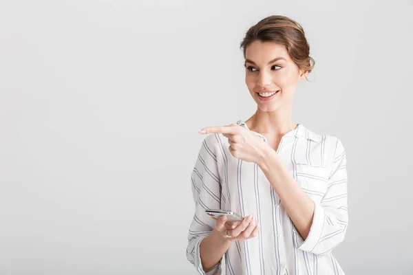 白い背景の上に孤立した携帯電話を使用し 脇指を指して楽しい女性のイメージ — ストック写真