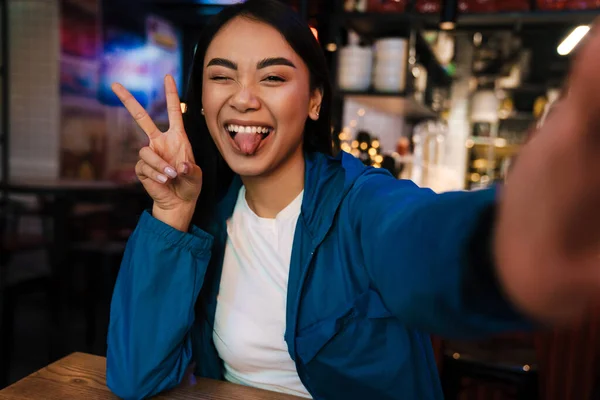 평화의 표시와 윙크를 하면서 카페에서 사진을 즐거운 이시아 여성의 — 스톡 사진
