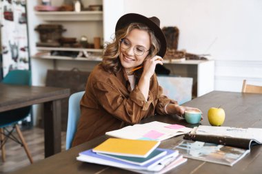 Gözlüklü neşeli bir kadının evde alıştırma kitaplarıyla çalışırken gülümsemesi.