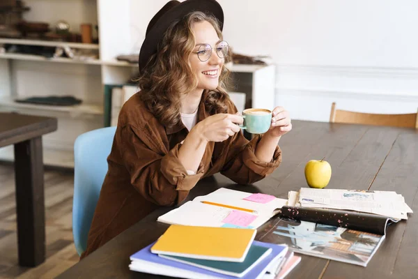 Imagen Alegre Encantadora Mujer Anteojos Bebiendo Café Mientras Estudia Con —  Fotos de Stock