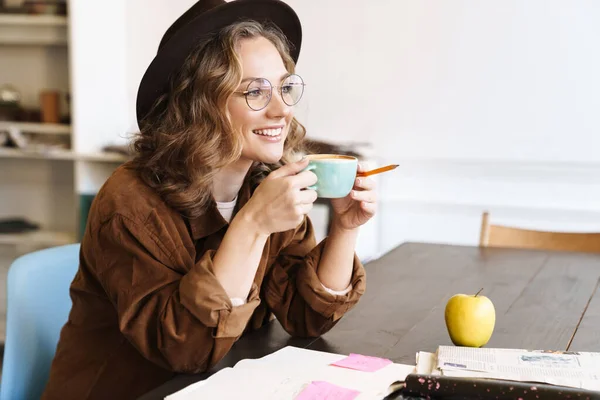自宅で運動書を勉強しながら眼鏡をかけコーヒーを飲みながら楽しい女性のイメージ — ストック写真
