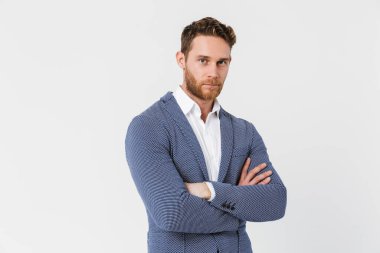 Tıraşsız, ceketli ve elleri çapraz pozlu genç bir adam resmi beyaz arka planda izole edilmiş.