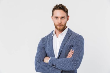 Tıraşsız, ceketli ve elleri çapraz pozlu genç bir adam resmi beyaz arka planda izole edilmiş.