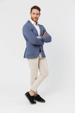 Ceket giyen, poz veren ve beyaz arka planda izole edilmiş kameraya bakan memnun genç bir adam görüntüsü