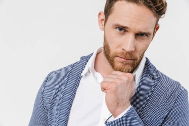 Ceket giyen, poz veren ve beyaz arka planda izole edilmiş kameraya bakan kendinden emin genç bir adam görüntüsü.