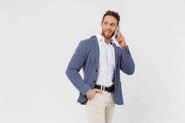 Beyaz arka planda izole edilmiş, gülümseyen ve akıllı telefondan konuşan ceketli yakışıklı bir adam görüntüsü