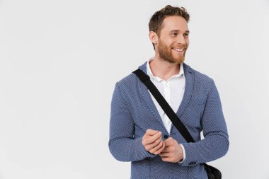 Ceketli gülümseyen bir genç adam resmi beyaz arka planda izole edilmiş bir çantayla kameraya poz veriyor.