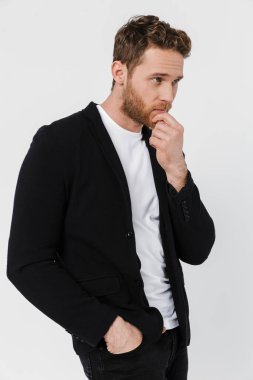 Ceketli, beyaz arka planda yalnız bir şekilde poz veren ve yan bakan yakışıklı adam görüntüsü.