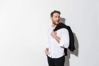 Siyah ceketli memnun bir adam görüntüsü ve beyaz arka planda izole edilmiş bir kenara bakıyor.