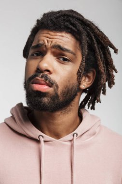 Beyaz arka planda tek başına duran kapüşonlu genç bir Afrikalı 'nın portresi.