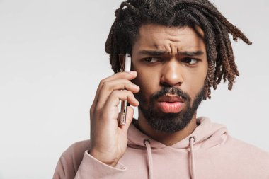 Kapüşonlu genç bir Afrikalı 'nın portresi. Beyaz arka planda tek başına duruyor, cep telefonuyla konuşuyor.