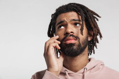 Kapüşonlu genç bir Afrikalı 'nın portresi. Beyaz arka planda tek başına duruyor, cep telefonuyla konuşuyor.