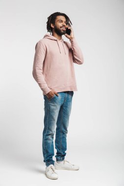 Beyaz arka planda izole edilmiş, cep telefonuyla konuşan kapüşonlu genç bir Afrikalı 'nın tam boy portresi.