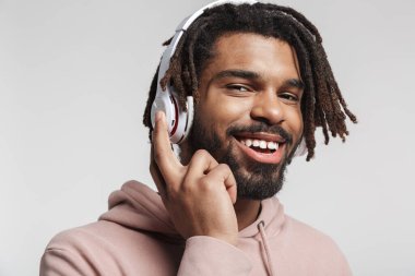 Beyaz arka planda izole edilmiş kablosuz kulaklık kullanan ve gülen Afro-Amerikan bir adamın portresi.