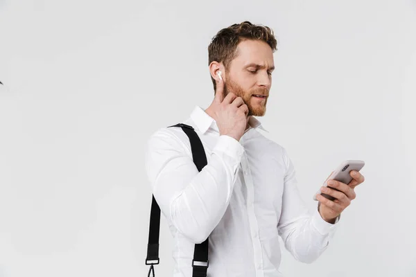 Image Brooding Blonde Man Using Cellphone Wireless Earphones Isolated White — Stock Photo, Image