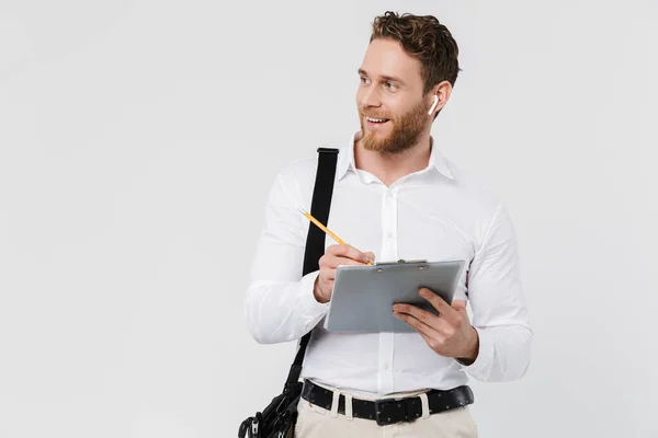 Imagem Homem Sorridente Fones Ouvido Sem Fio Segurando Prancheta Escrita — Fotografia de Stock