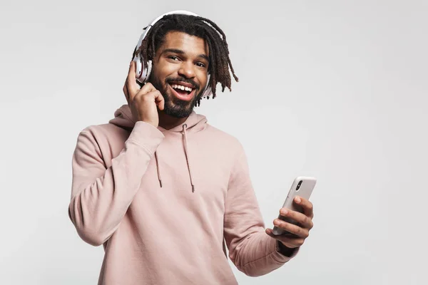 用手机和无线耳机隔离在白色背景下的兴奋的非洲裔美国人的画像 — 图库照片
