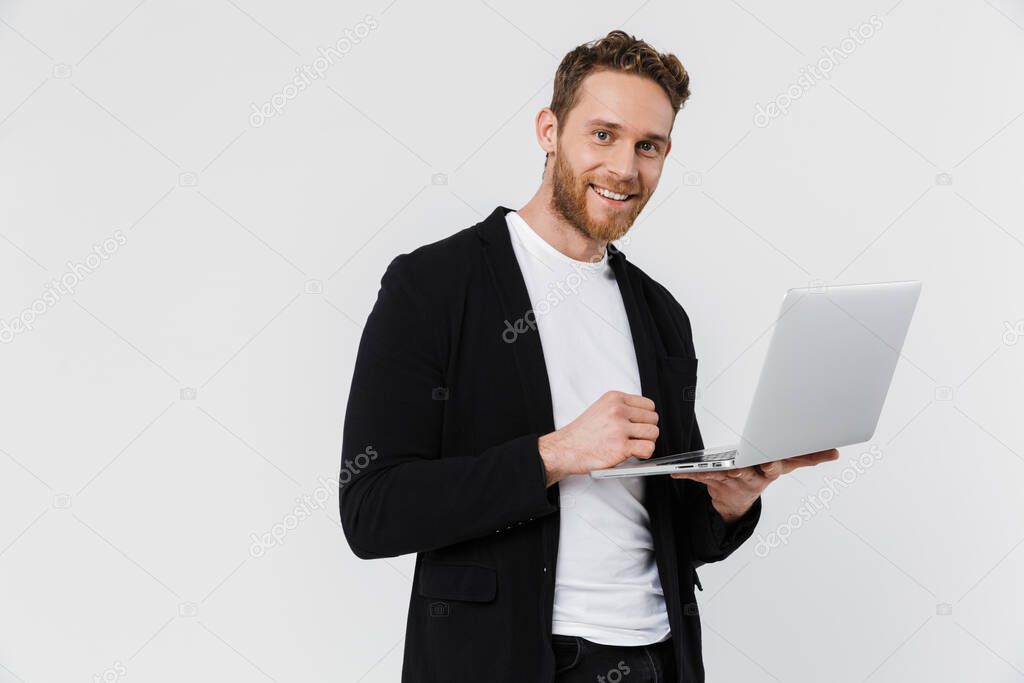 Image of handsome pleased man in jacket smiling and using laptop isolated over white background