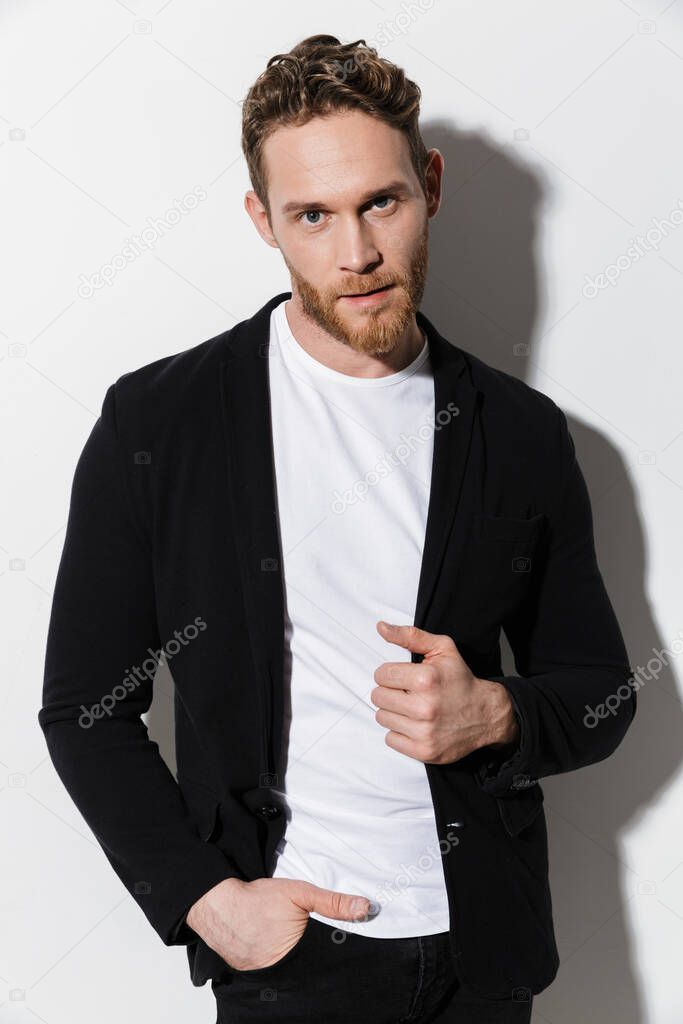 Image of unshaven confident man in jacket posing and looking at camera isolated over white background