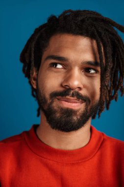 Mutlu bir Afrikalı Amerikalının portresi yukarı bakıyor ve gülümsüyor mavi arka planda.