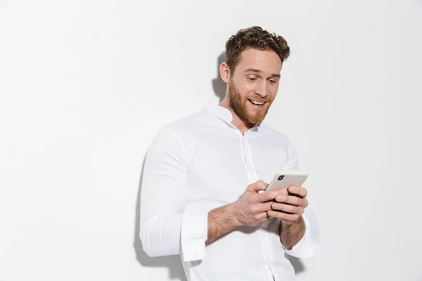 Изображение Красивого Радостного Мужчины Рубашке Печатающего Мобильном Телефоне Улыбающегося Изолированно — стоковое фото