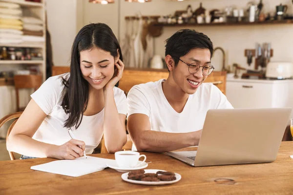 Imagem Casal Multicultural Sorridente Fazendo Anotações Planejador Usando Laptop Cozinha — Fotografia de Stock