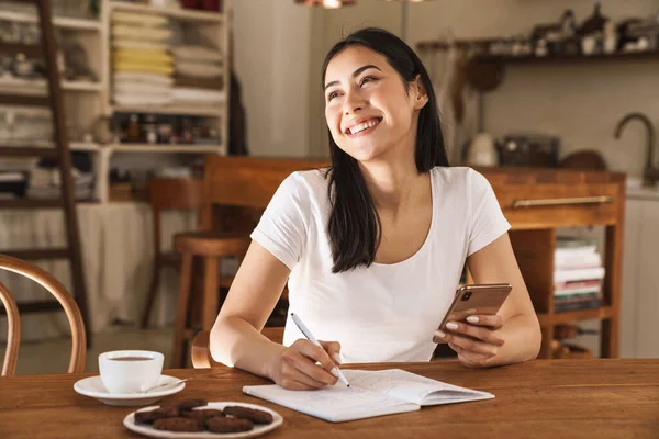 Imagem Mulher Branca Sorrindo Fazendo Anotações Planejador Usando Telefone Celular — Fotografia de Stock