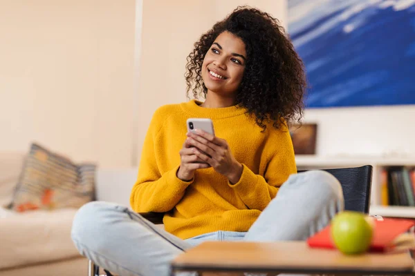 Imagem Uma Mulher Afro Americana Sorrindo Usando Celular Enquanto Senta — Fotografia de Stock