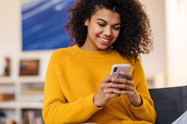 Imagem Uma Mulher Afro Americana Sorrindo Usando Celular Enquanto Senta — Fotografia de Stock