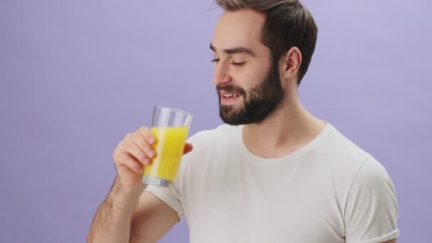 티셔츠를 잘생긴 젊은이가 오렌지 주스를 마시며 고립된 있습니다 — 비디오