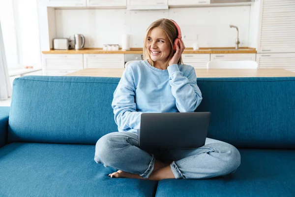 Imagen Una Linda Mujer Sonriente Usando Portátil Auriculares Inalámbricos Mientras —  Fotos de Stock