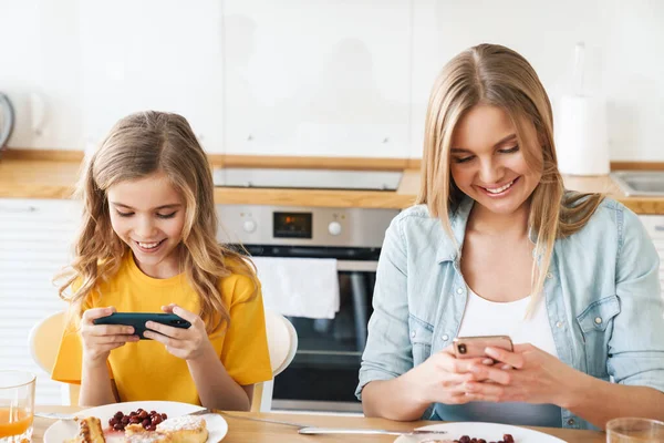 Foto Madre Hija Caucásicas Complacidas Usando Teléfonos Celulares Mientras Desayunan — Foto de Stock