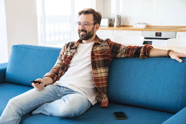 Porträtt Ung Glad Skäggig Man Ler Och Tittar Medan Sitter — Stockfoto