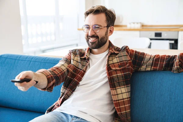 Porträtt Ung Glad Skäggig Man Ler Och Tittar Medan Sitter — Stockfoto