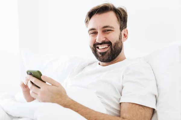 Image Young Unshaven Caucasian Man Smiling Using Cellphone While Lying — Stock Photo, Image