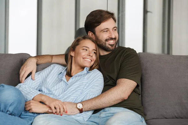 Foto Casal Caucasiano Alegre Sorrindo Abraçando Enquanto Sentado Sofá Casa — Fotografia de Stock