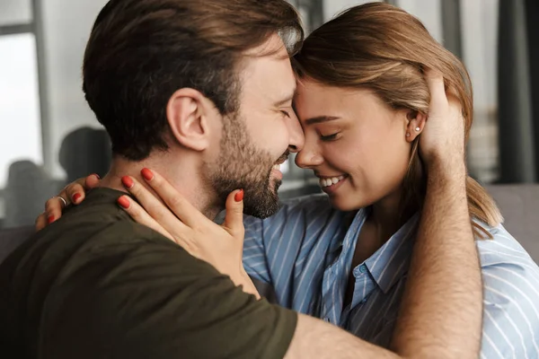 Foto Casal Caucasiano Romântico Alegre Sorrindo Abraçando Enquanto Sentado Sofá — Fotografia de Stock