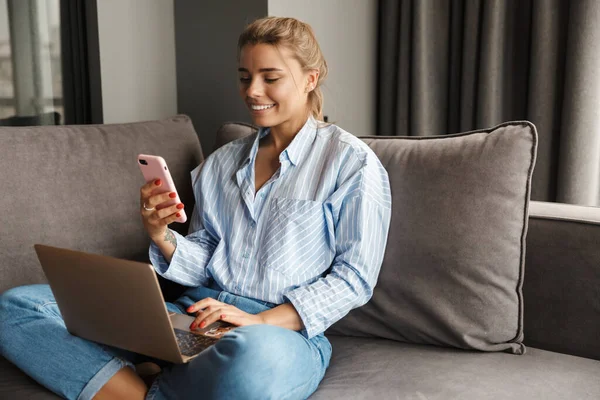 Imagem Bela Jovem Mulher Sorridente Usando Laptop Falando Celular Enquanto — Fotografia de Stock