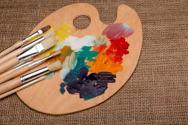 Wooden palette with paints and brushes — Free Stock Photo