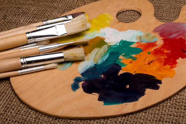 Wooden palette with paints and brushes — Free Stock Photo