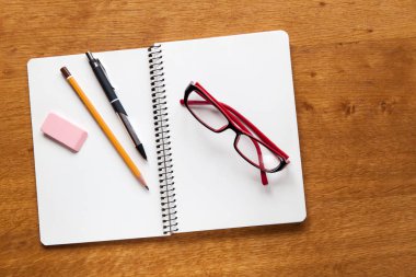Arka plan için ahşap masa üzerinde açık defter ve okul veya office araçları Üstten Görünüm