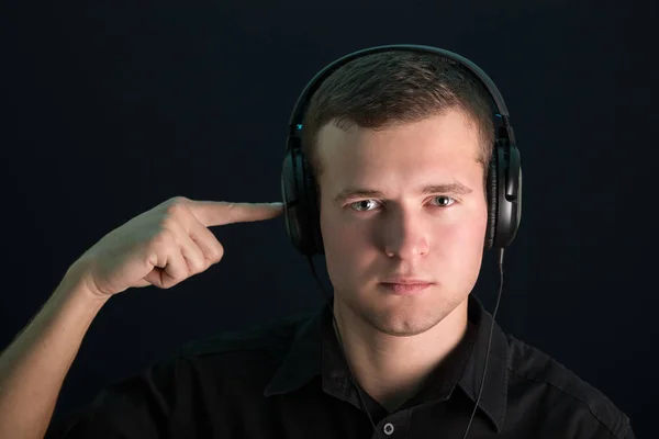 Portrait of young guy with headphones on the dark background Royalty Free Stock Images