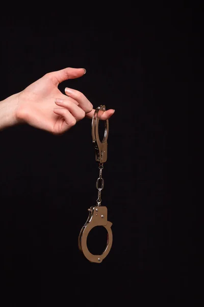 Female hand holding handcuffs on a dark background — Stock Photo, Image