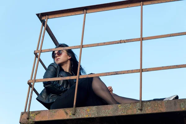 Portret dziewczyny brunetka, w ciemnych ubraniach, siedząc na balkonie — Zdjęcie stockowe