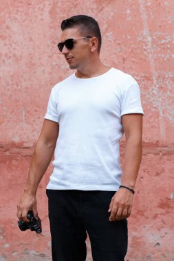 Pembe duvar backg önünde Beyaz gömlekli retro kamera ile adam