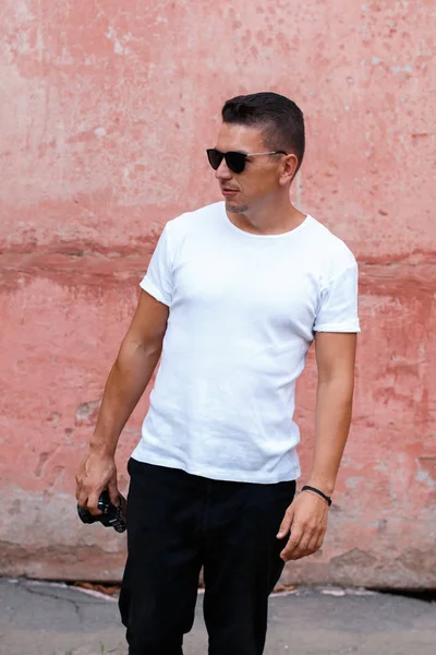 Pembe duvar backg önünde Beyaz gömlekli retro kamera ile adam