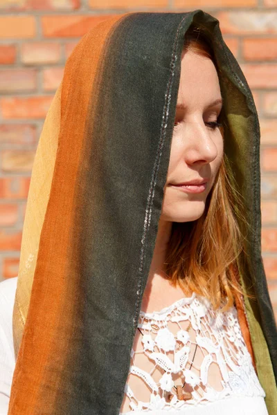 Κορίτσι με το μαντήλι που καλύπτει το κεφάλι σε ένα φόντο τούβλο — Φωτογραφία Αρχείου